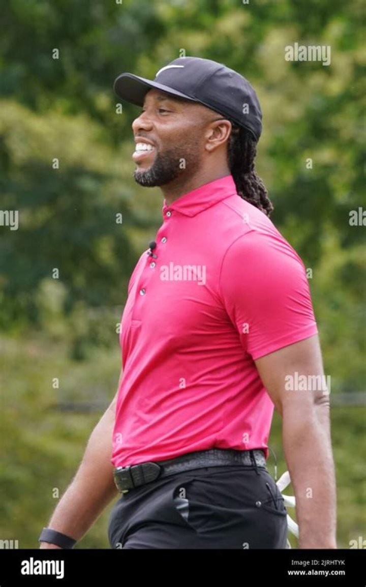 Larry Fitzgerald is walking in Seattle, Washington wearing dark blue tuxedo and a check tie with a white undershirt